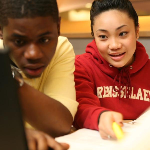 Two students working on a laptop as part of a group project.