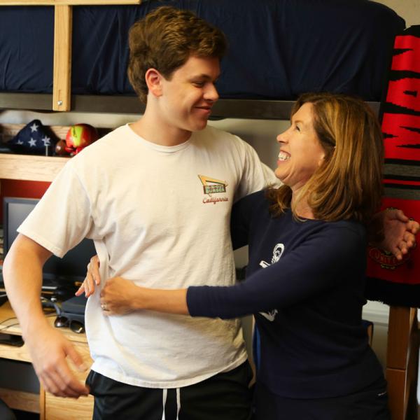 Mother and son embrace in dorm room during Family Weekend